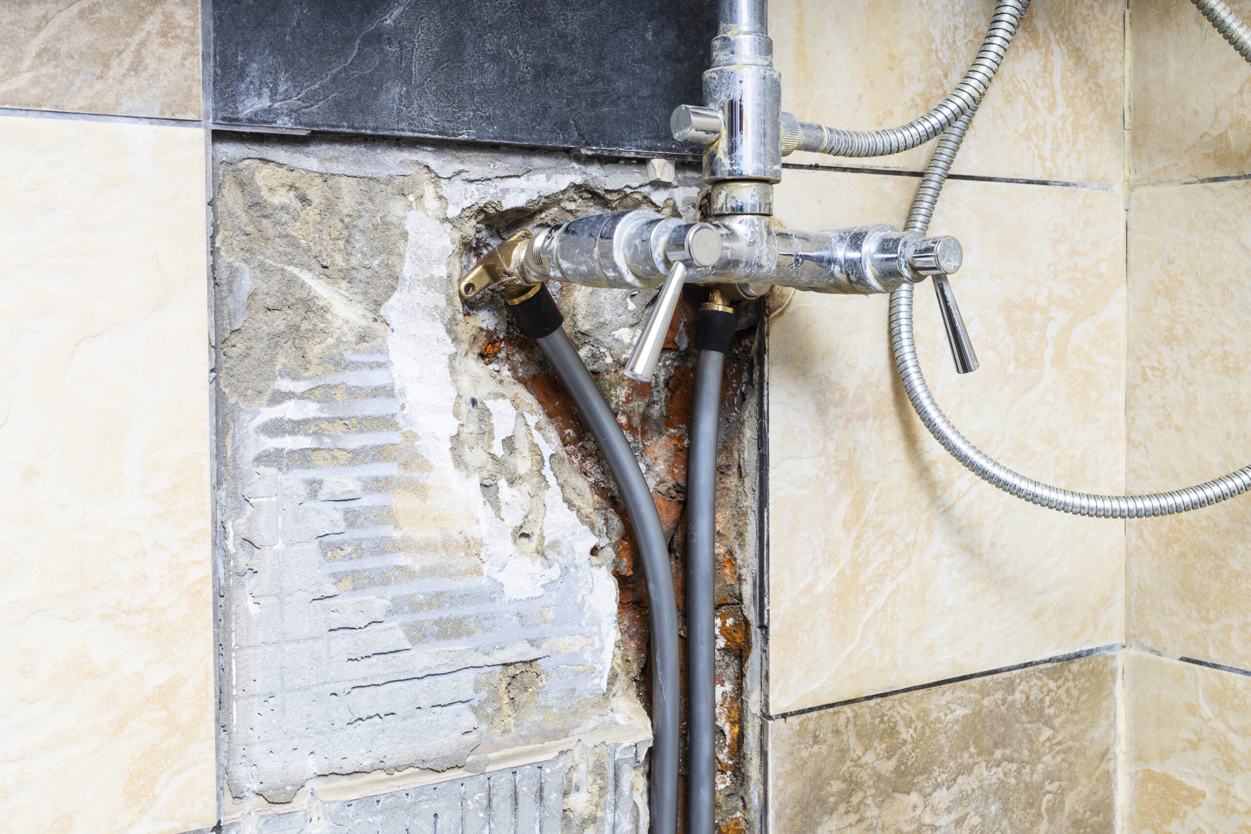 leaking shower water pipes connected to faucet inside broken wall