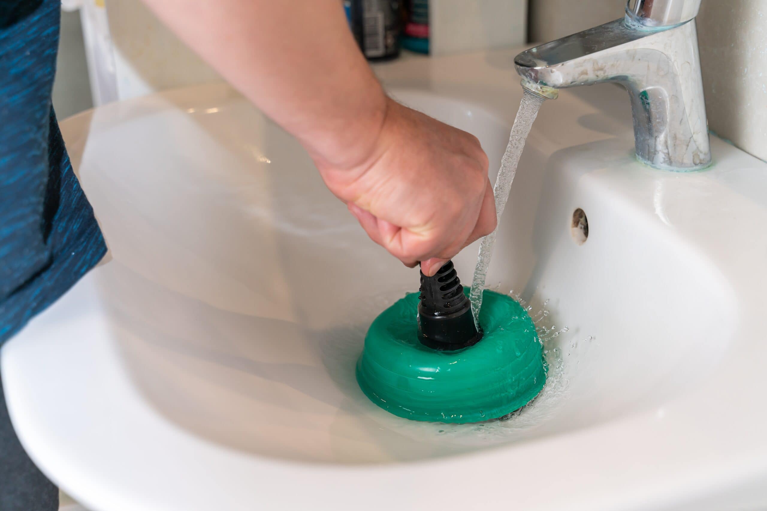 Plumber using force cup to unclog sink drain in bathroom