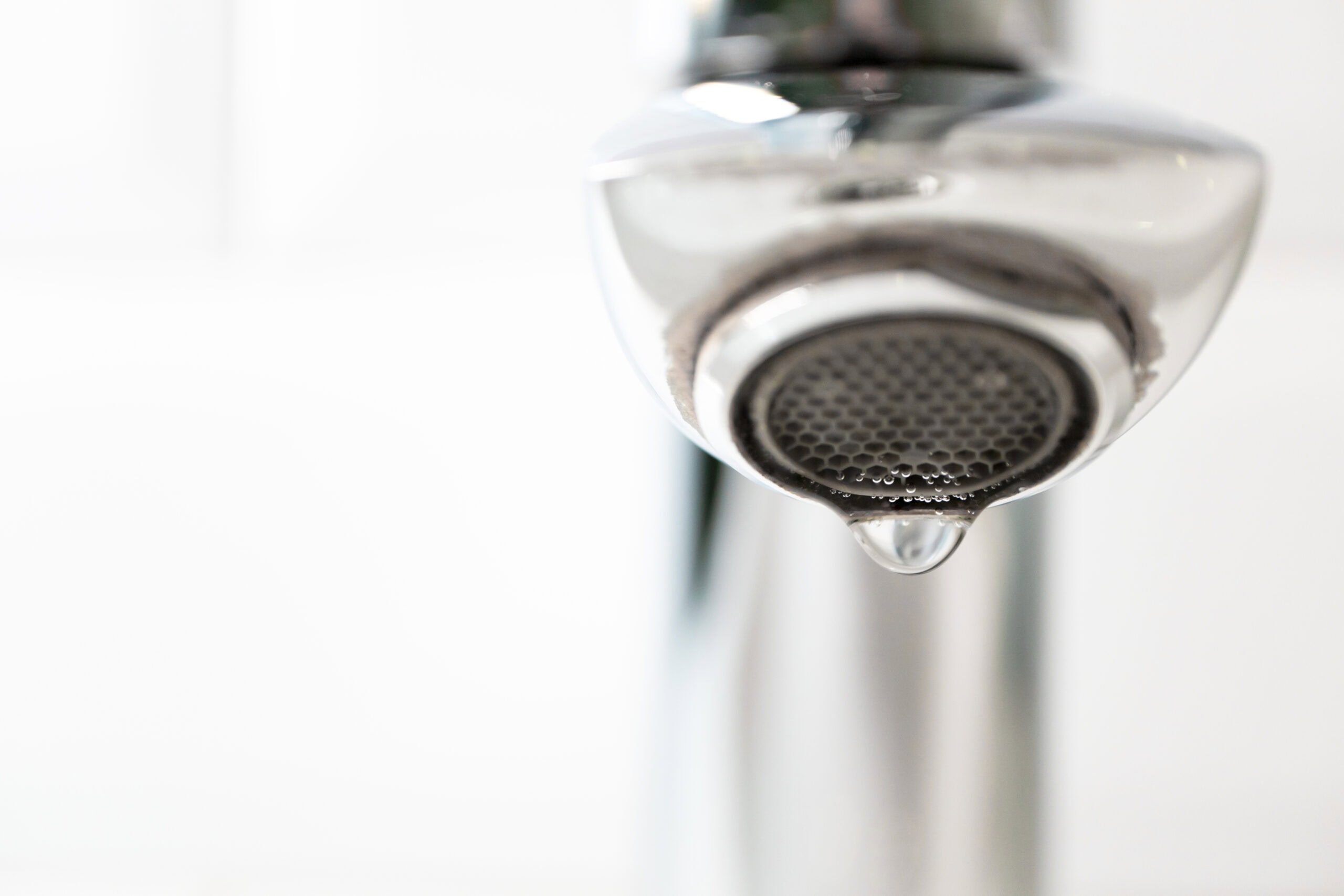Closeup photo of a shower head with limescale due to hard water on a white background